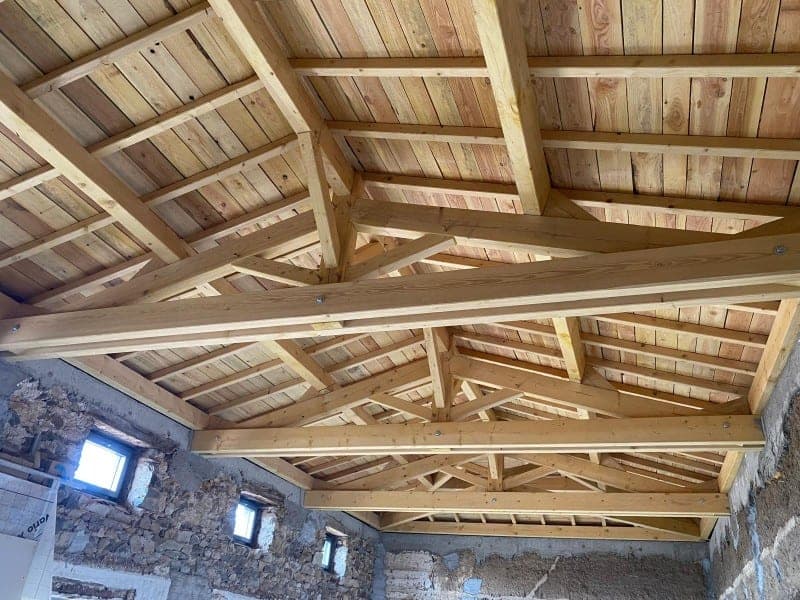 Charpente traditionnelle apparente en bois neuf sur une maison en pierre à Champoly