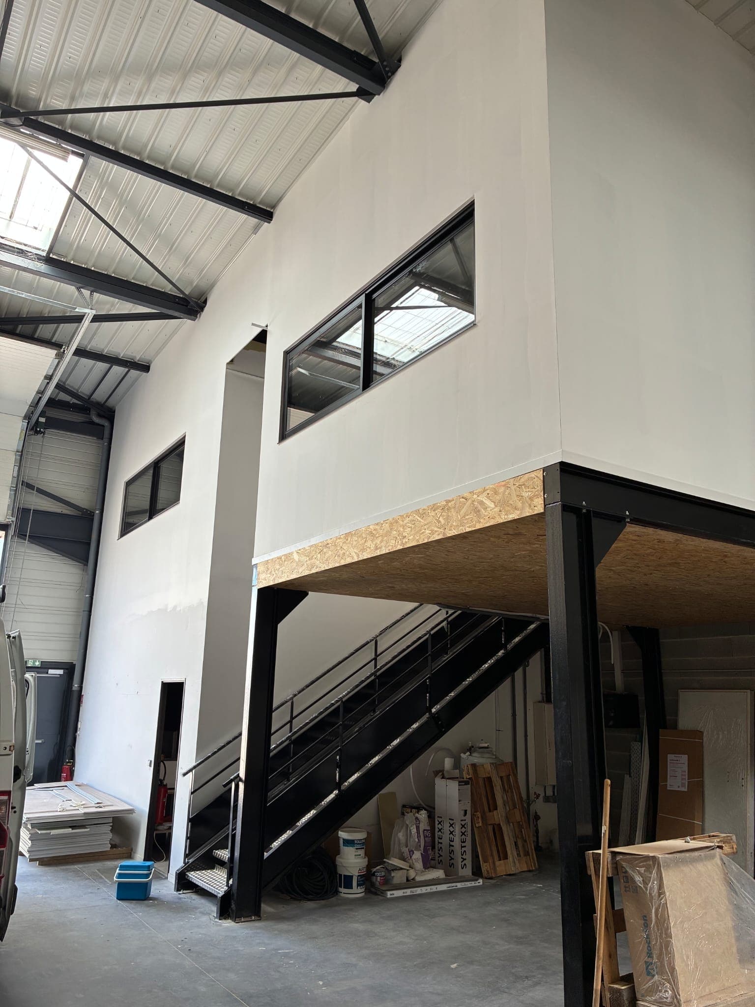 Mezzanine à plancher bois créée dans un atelier, avec escalier métallique